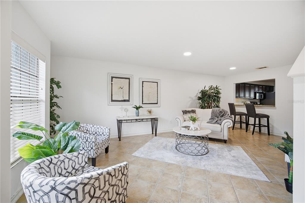 A living room features tile flooring, patterned armchairs, a white sofa, and a kitchen pass-through — 5100 BURCHETTE ROAD UNIT 2701, TAMPA, FL