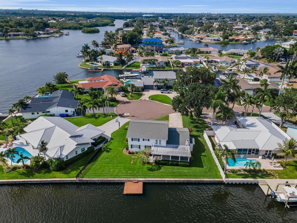 An aerial view shows three waterfront houses with pools along a canal in a neighborhood — 1310 41ST AVENUE NE, ST PETERSBURG, FL