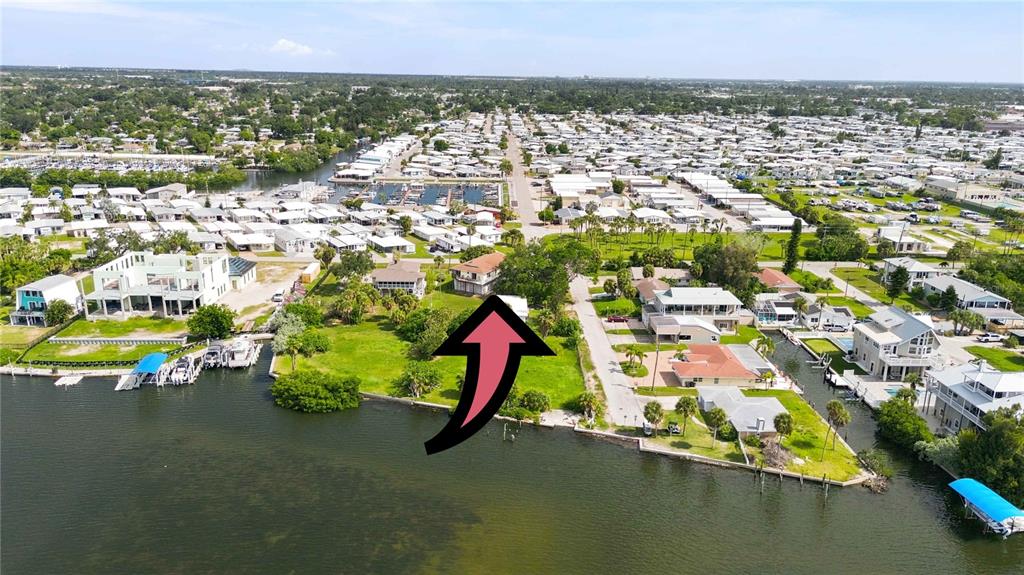 An aerial view shows a waterfront property with a large grassy lot and a house — 6904 22ND STREET W, BRADENTON, FL