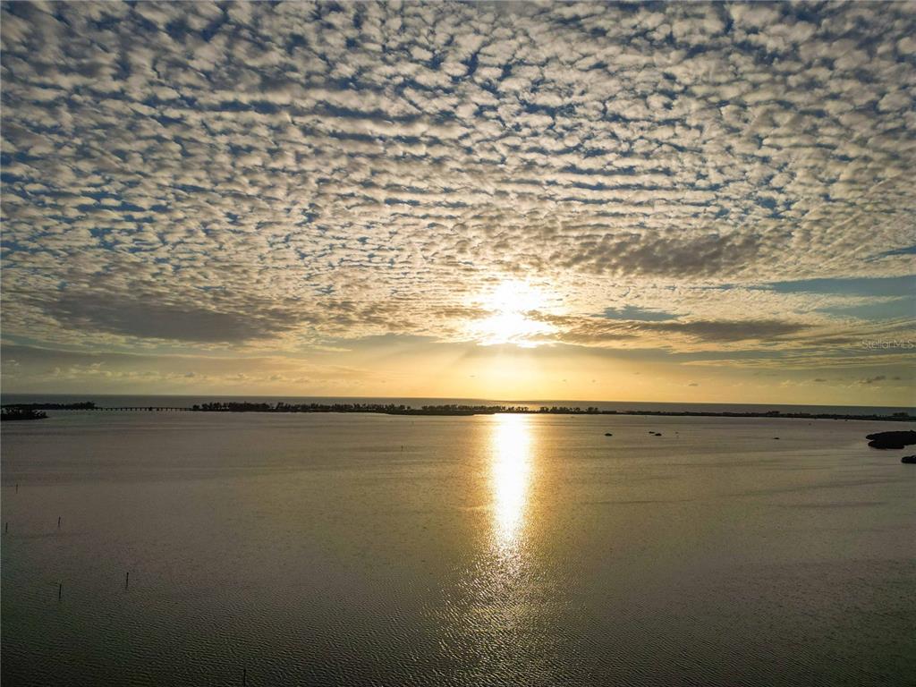 An aerial view of a sunset over a calm body of water with distant land — 6904 22ND STREET W, BRADENTON, FL