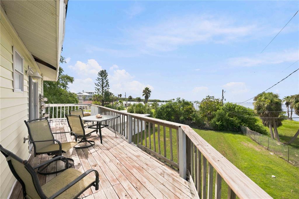 A wooden deck with patio furniture overlooks a grassy yard and a body of water — 6904 22ND STREET W, BRADENTON, FL