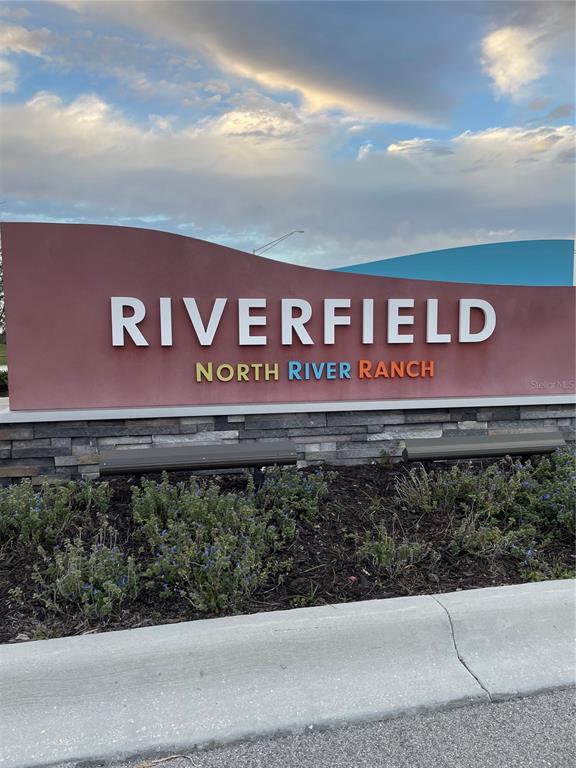 A sign for Riverfield at North River Ranch stands above a stone base and landscaping — 8443 CANYON CREEK TRAIL, PARRISH, FL
