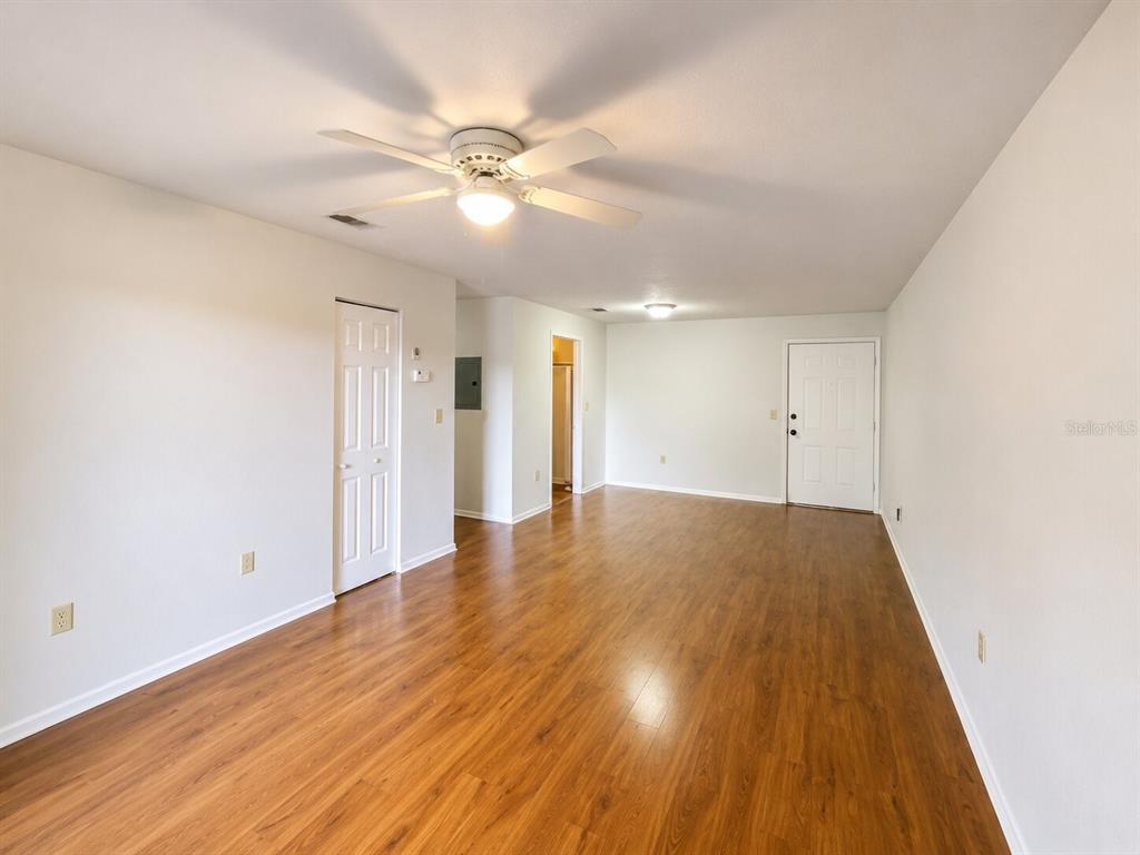 An empty living room features wood-look flooring, a ceiling fan, and a white entry door — 926 LAKE DESTINY ROAD UNIT G, ALTAMONTE SPRINGS, FL