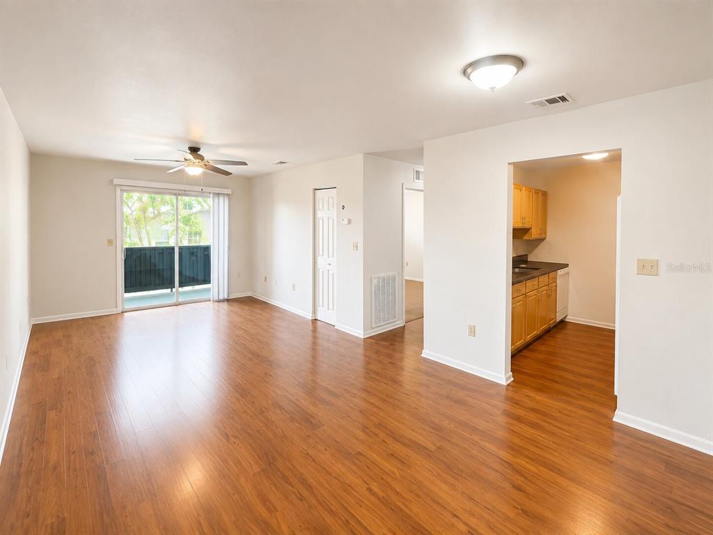 An open living area with wood-look flooring, a ceiling fan, and an adjacent kitchen — 926 LAKE DESTINY ROAD UNIT G, ALTAMONTE SPRINGS, FL
