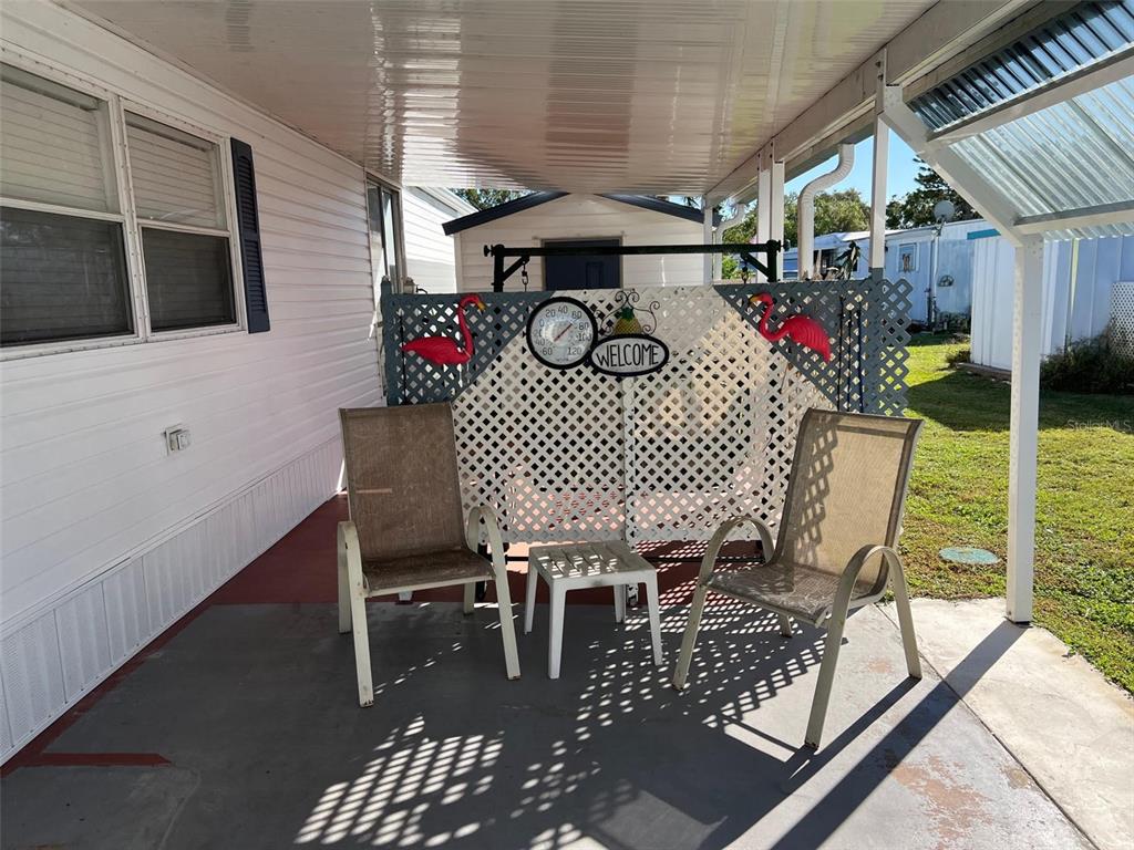 A covered patio features two chairs, a small table, and a decorative lattice privacy screen — 11300 124TH AVENUE UNIT 150, LARGO, FL