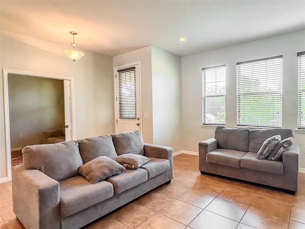 A living room with tile flooring, a front door, and a grey sofa set — 8607 RANDAL PARK BOULEVARD, ORLANDO, FL