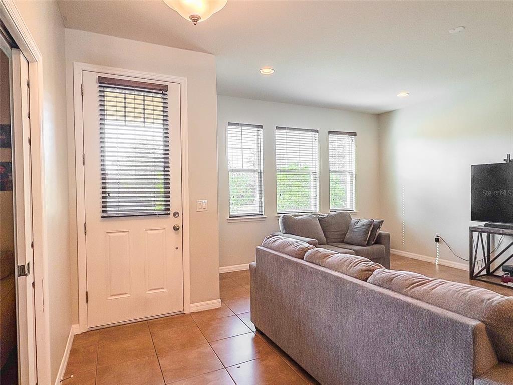 A living room with tile floors, a television on a stand, and an open kitchen — 8607 RANDAL PARK BOULEVARD, ORLANDO, FL