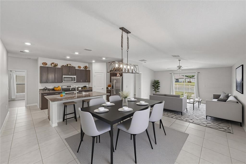 A kitchen with dark cabinets and a granite island opens into a large tiled living area — 4334 TROTTERS WAY, LAKELAND, FL