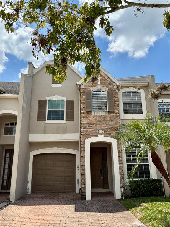 A two-story townhouse with a stone facade, a single-car garage, and a brick driveway — 547 TERRACE SPRING DRIVE, ORLANDO, FL