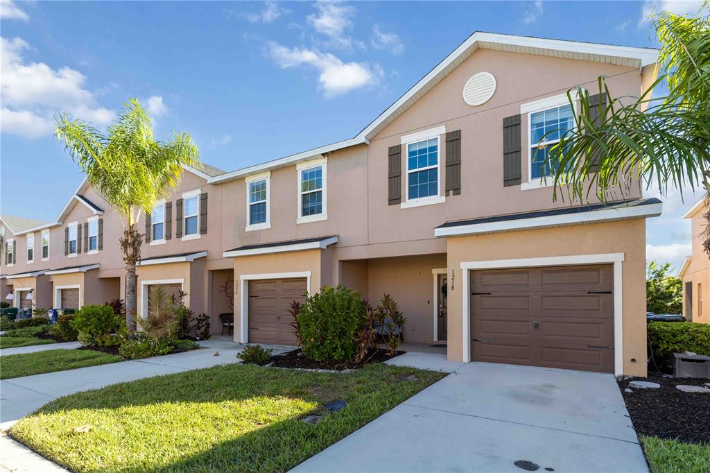 A two-story townhouse with a tan stucco exterior, a single-car garage, and a palm tree — 1218 GRANTHAM DRIVE, SARASOTA, FL