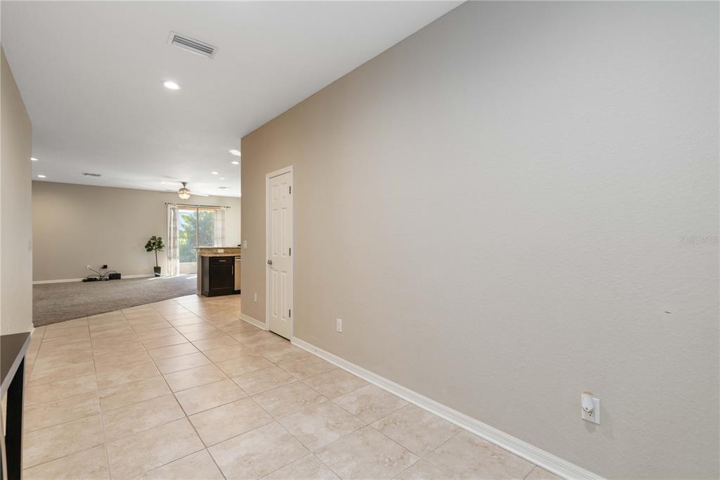 A tiled hallway leads to a carpeted living area with a kitchen in the background — 1218 GRANTHAM DRIVE, SARASOTA, FL