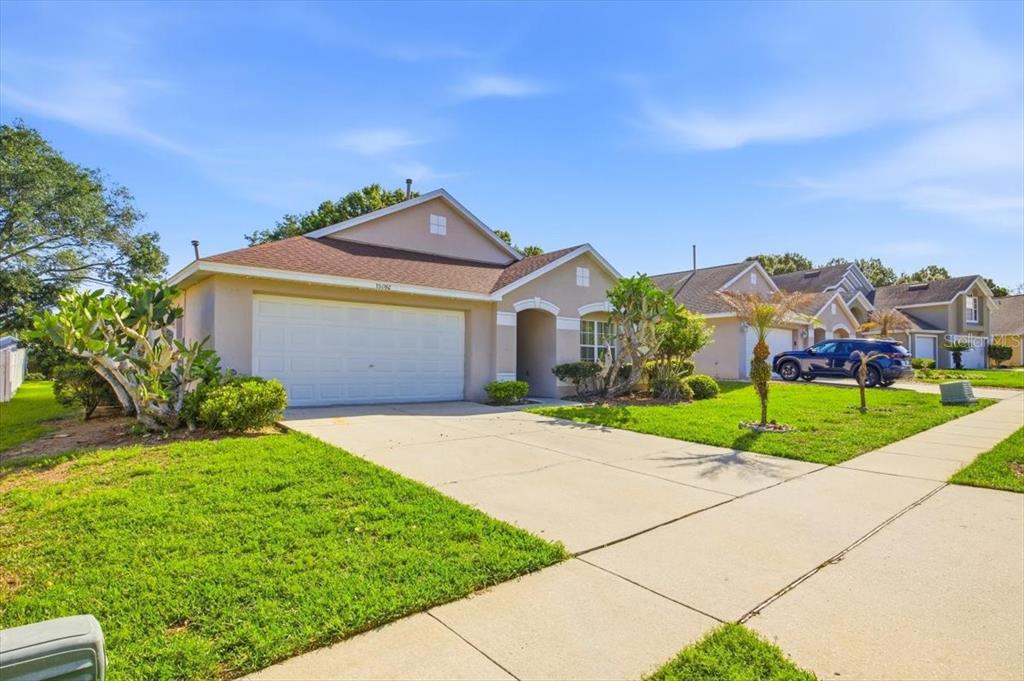A single-story suburban house with a two-car garage and a concrete driveway — 15702 BAY VISTA DRIVE, CLERMONT, FL