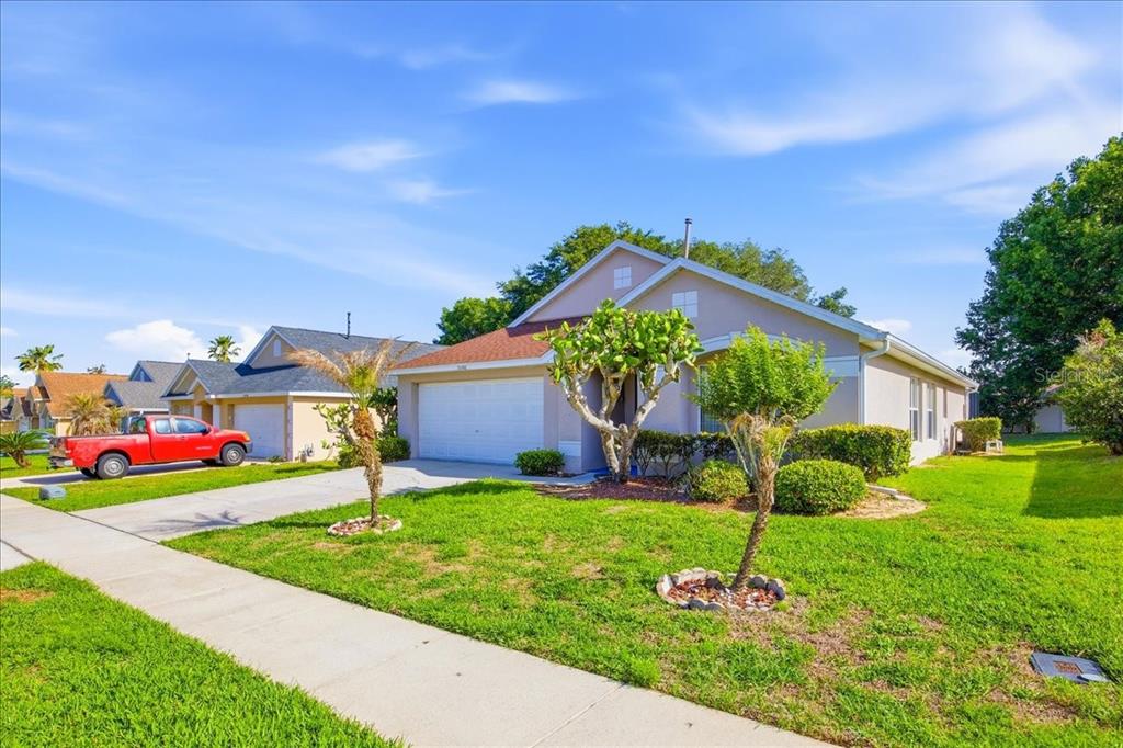 A single-story suburban house with a two-car garage, a red truck, and landscaped front yard — 15702 BAY VISTA DRIVE, CLERMONT, FL