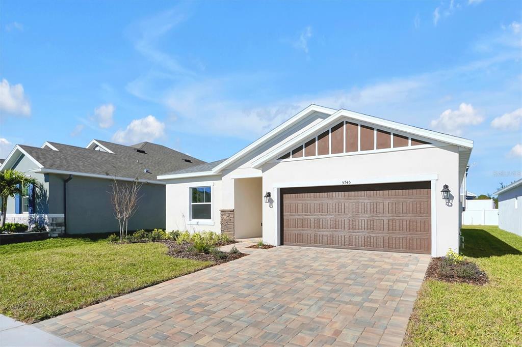 A single-story house with a paved driveway, two-car garage, and light-colored stucco exterior — 5745 WALLIS LANE, ST CLOUD, FL