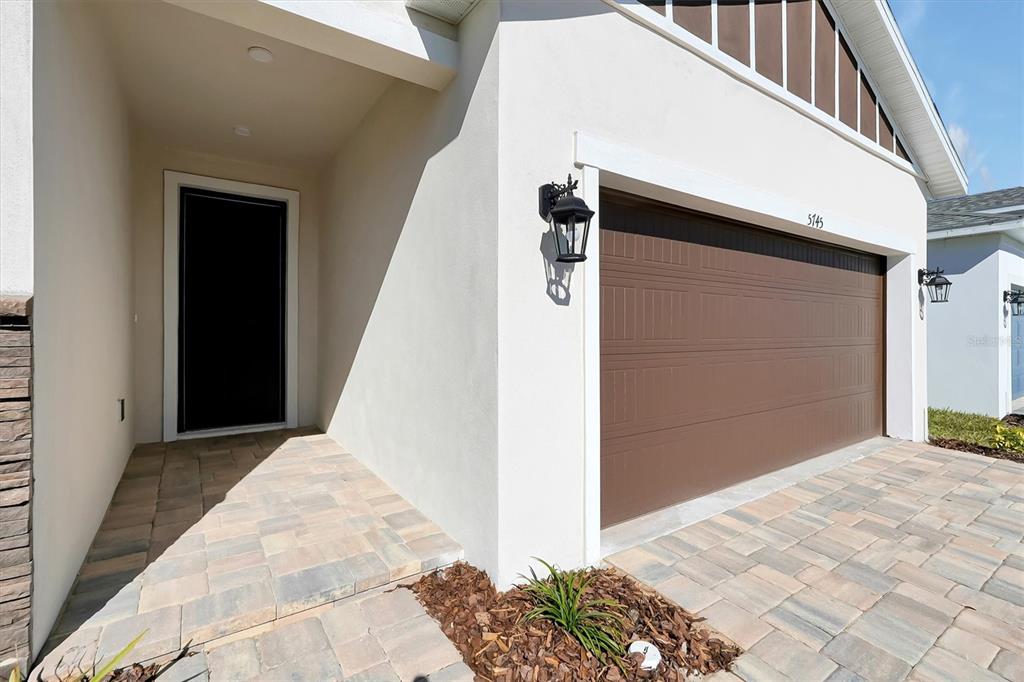 A paved walkway leads to the front entrance and a brown garage door of a house — 5745 WALLIS LANE, ST CLOUD, FL