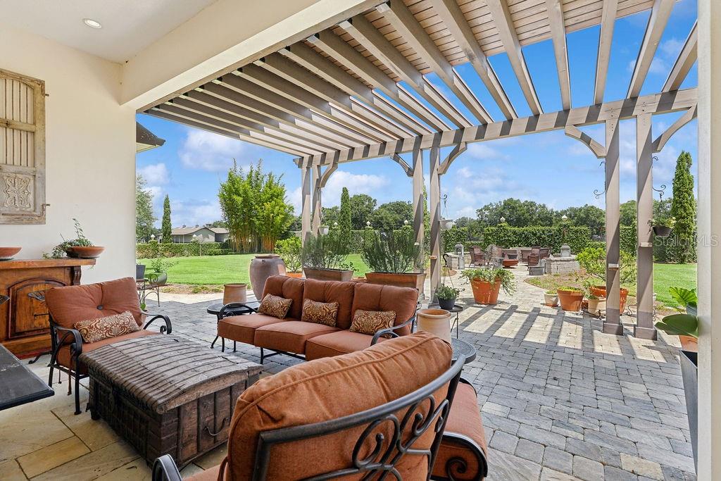 A covered patio features a wooden pergola, outdoor furniture, and a view of the backyard — 11408 N MAGNOLIA AVENUE, OCALA, FL