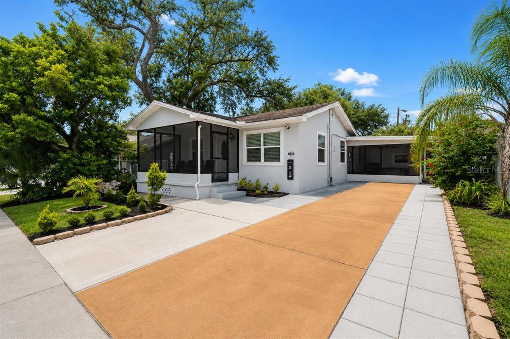 A single-story house with a screened front porch, a paved driveway, and mature landscaping — 8912 N 40TH STREET, TAMPA, FL