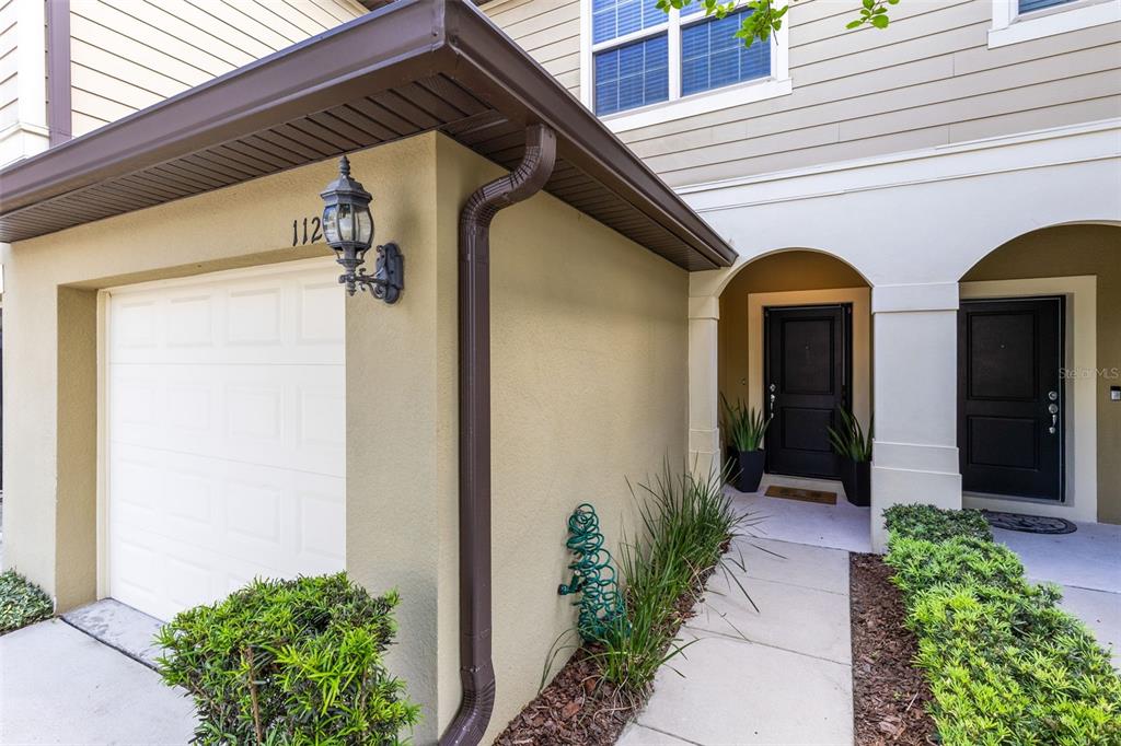 The exterior of a townhouse features a garage, a covered entryway, and two black doors — 1120 PAVIA DRIVE, APOPKA, FL