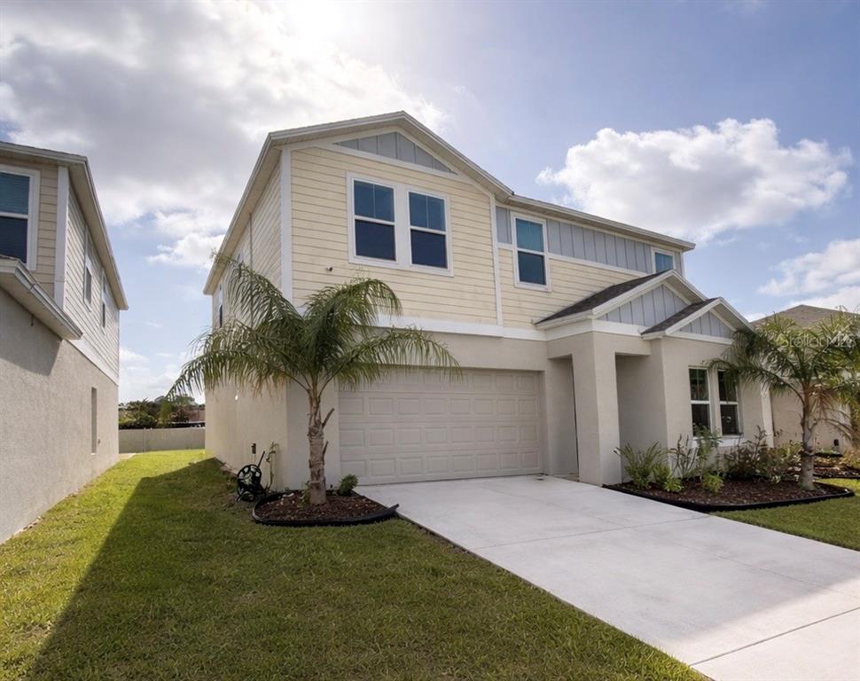 A two-story house with light yellow siding, a concrete driveway, and a two-car garage — 1392 AXEL CIR, WINTER HAVEN, FL