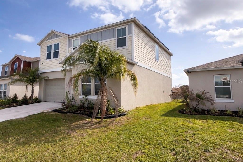 A two-story suburban house with a beige stucco and siding exterior and a palm tree — 1392 AXEL CIR, WINTER HAVEN, FL
