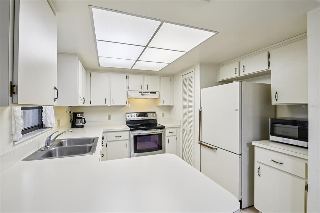 A kitchen with white cabinets, white appliances, a double sink, and a drop ceiling light — 3826 PARAPET DRIVE, COCOA, FL