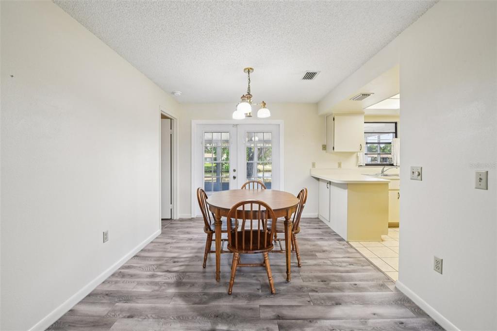 A dining area features wood-look flooring, a round wooden table with chairs, and glass doors — 3826 PARAPET DRIVE, COCOA, FL