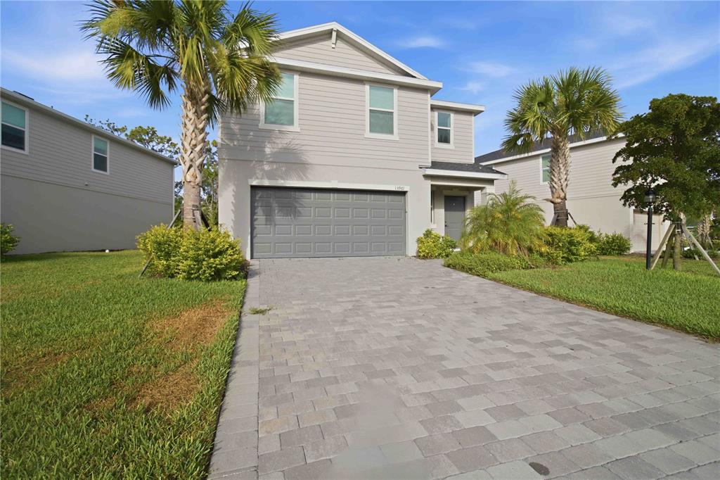 A two-story house with light gray siding, a two-car garage, and palm trees — 13961 LILAC SKY TERRACE, BRADENTON, FL