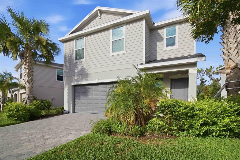 A two-story house with light gray siding, a gray garage door, and a paved driveway — 13961 LILAC SKY TERRACE, BRADENTON, FL