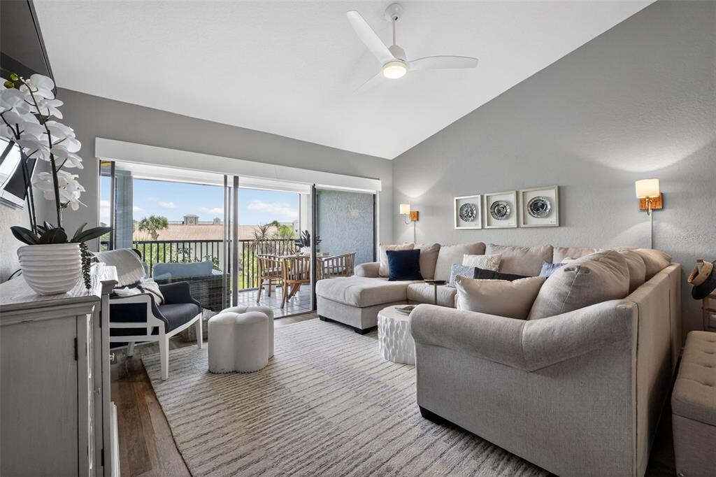 An outdoor covered walkway features a white railing, beige stucco walls, and a screen door — 443 BOUCHELLE DRIVE UNIT 302, NEW SMYRNA BEACH, FL