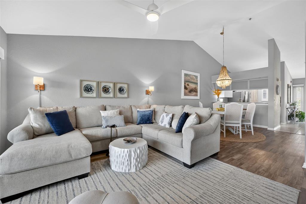 A dining area with a round table and chandelier sits adjacent to a living room — 443 BOUCHELLE DRIVE UNIT 302, NEW SMYRNA BEACH, FL