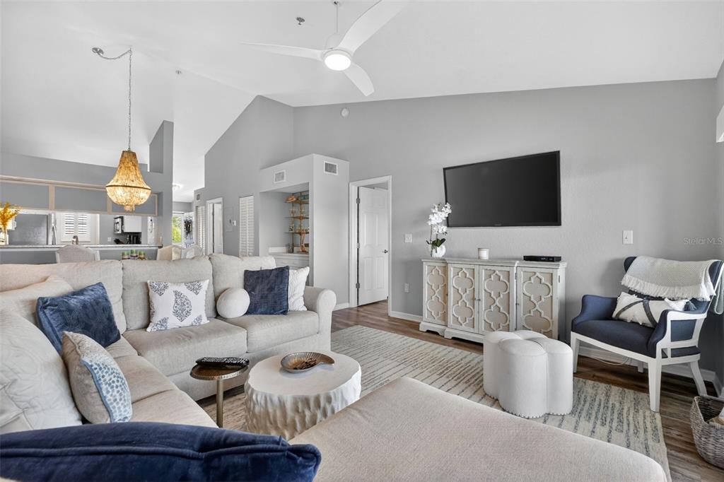 A living room features a large sectional sofa, a textured coffee table, and vaulted ceilings — 443 BOUCHELLE DRIVE UNIT 302, NEW SMYRNA BEACH, FL