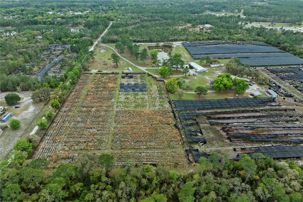 An aerial view shows a rural property with agricultural fields, shade structures, and a pond — 40945 BEACH, EUSTIS, FL