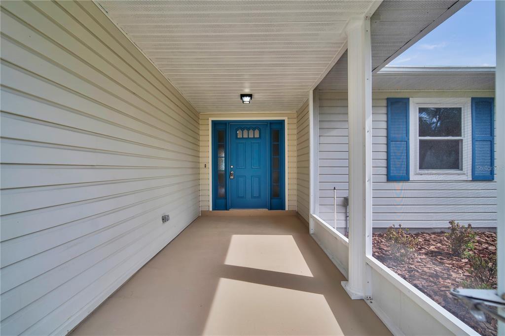 A covered front porch with light siding, a blue front door, and a screened enclosure — 2314 BONNIE VIEW COURT, LEESBURG, FL