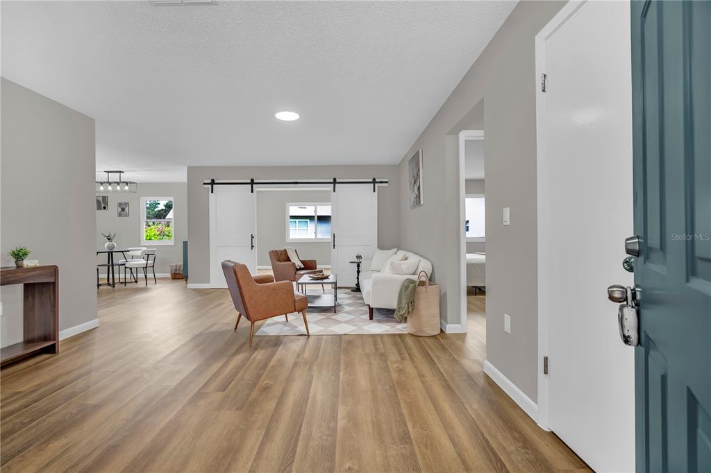 A view from an entryway into a living room with wood-look flooring and barn doors — 2314 BONNIE VIEW COURT, LEESBURG, FL