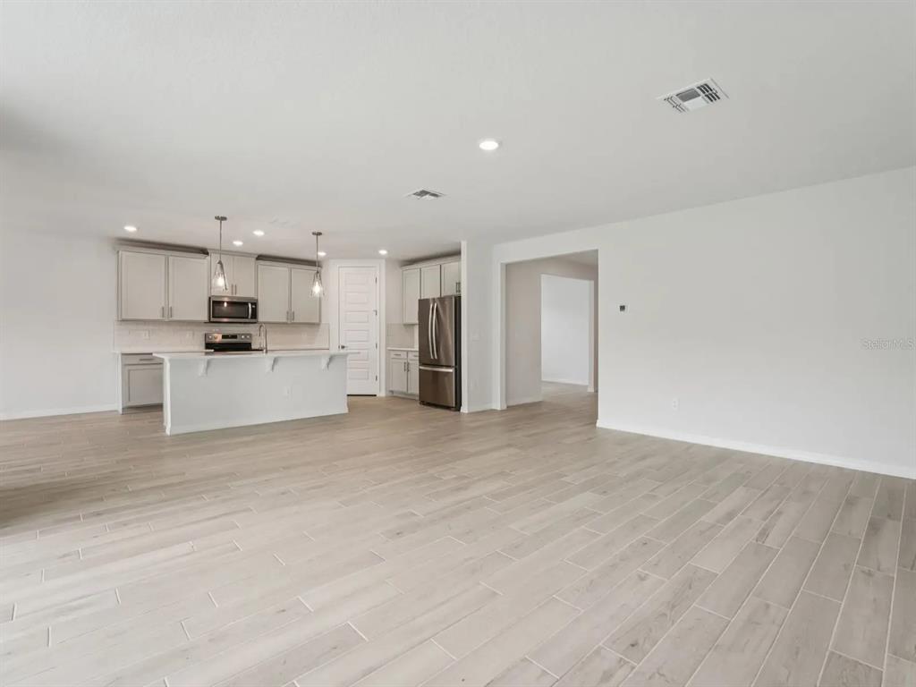 This is a digital rendering of a modern kitchen featuring white cabinetry, stainless appliances, and island seating — 3313 ORCHARD LOOP, BARTOW, FL