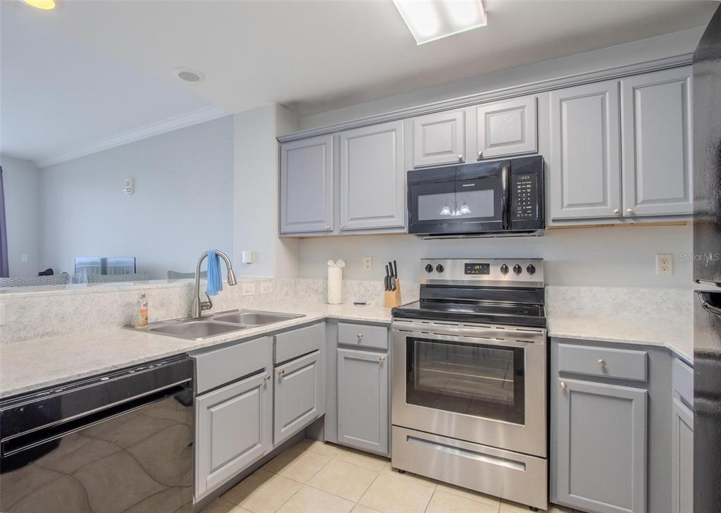 A living room features a glass coffee table, a television, and a balcony overlooking water — 13415 BLUE HERON BEACH DRIVE UNIT 407, ORLANDO, FL
