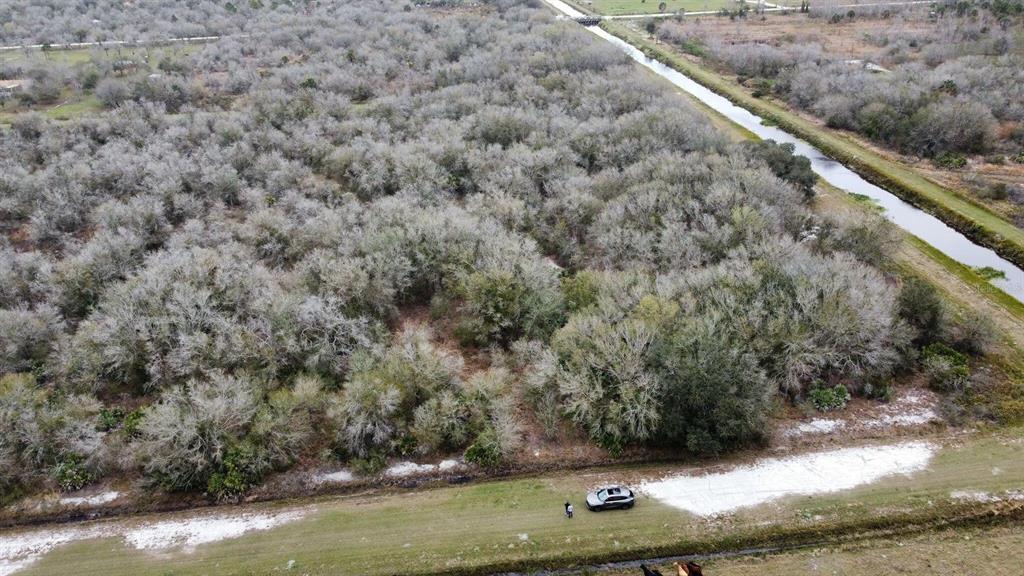 An aerial view shows a wooded lot bordered by a canal and a dirt road — 15839 NW 252ND STREET, OKEECHOBEE, FL