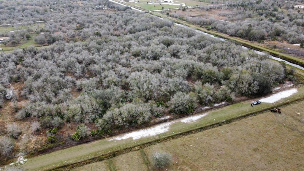 An aerial view shows a wooded lot bordered by a canal and a grassy field — 15839 NW 252ND STREET, OKEECHOBEE, FL