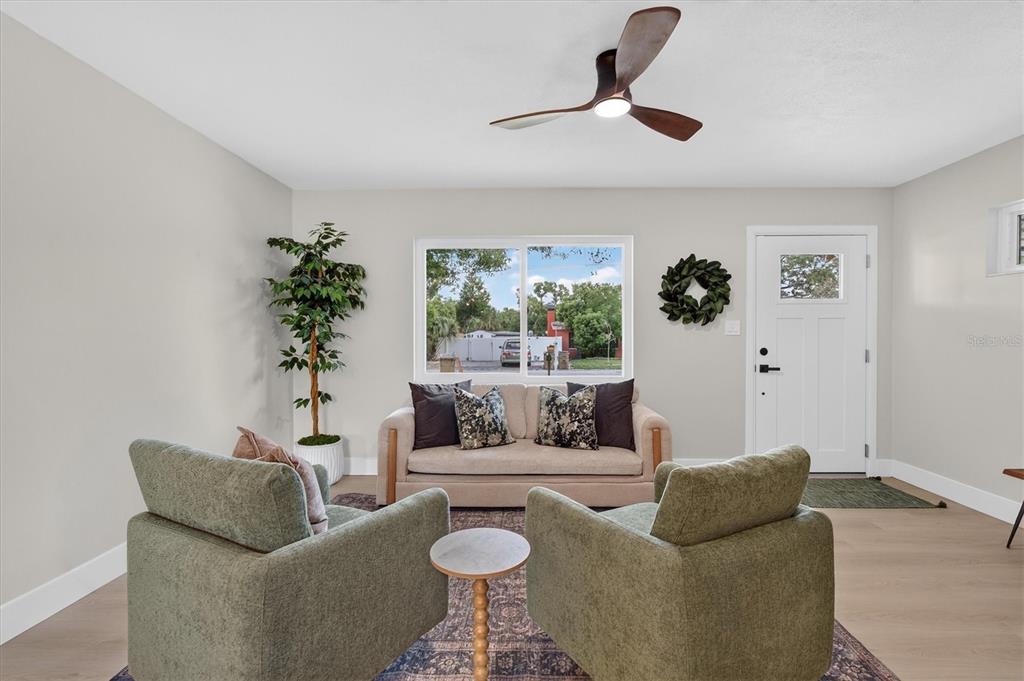 A living room features a sofa, two armchairs, a ceiling fan, and a front door — 5305 E 98TH AVENUE, TEMPLE TERRACE, FL