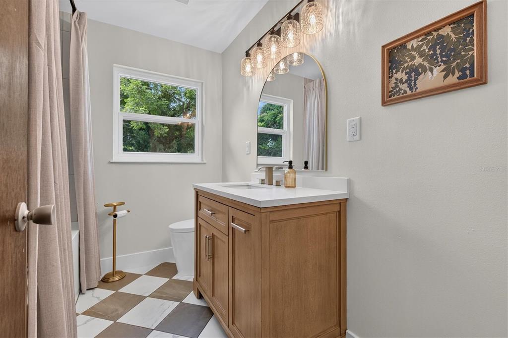 A galley kitchen features light wood cabinets, white countertops, and a view into a dining room — 5305 E 98TH AVENUE, TEMPLE TERRACE, FL