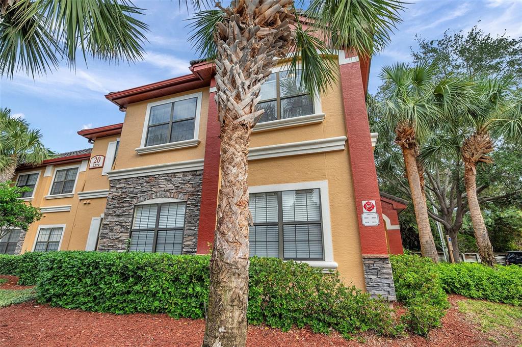 A dining area with a glass table and metal chairs opens into a living room — 2279 PORTOFINO PLACE UNIT 20-202, PALM HARBOR, FL