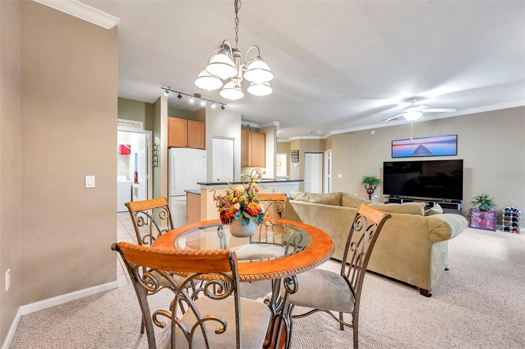 A dining area with a glass-topped table sits in front of a living room space — 2279 PORTOFINO PLACE UNIT 20-202, PALM HARBOR, FL