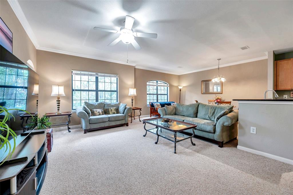 An open-concept living room features a blue sofa, a glass coffee table, and a kitchen — 2279 PORTOFINO PLACE UNIT 20-202, PALM HARBOR, FL