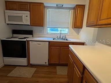 A kitchen features wooden cabinets, white appliances, a sink, and light-colored countertops — 720B E MINNESOTA AVENUE UNIT B, DELAND, FL