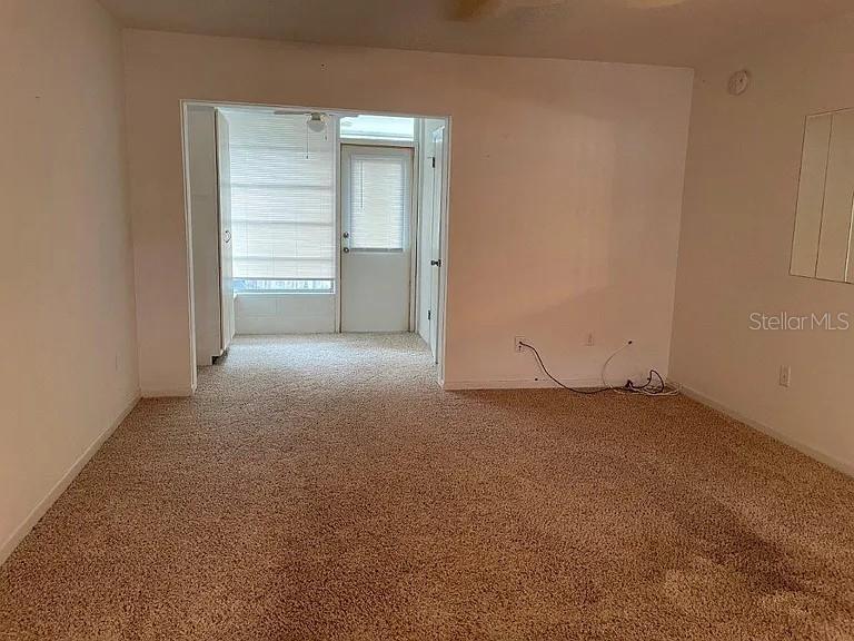 A carpeted living room leads to a sunroom with a glass door and blinds — 720B E MINNESOTA AVENUE UNIT B, DELAND, FL