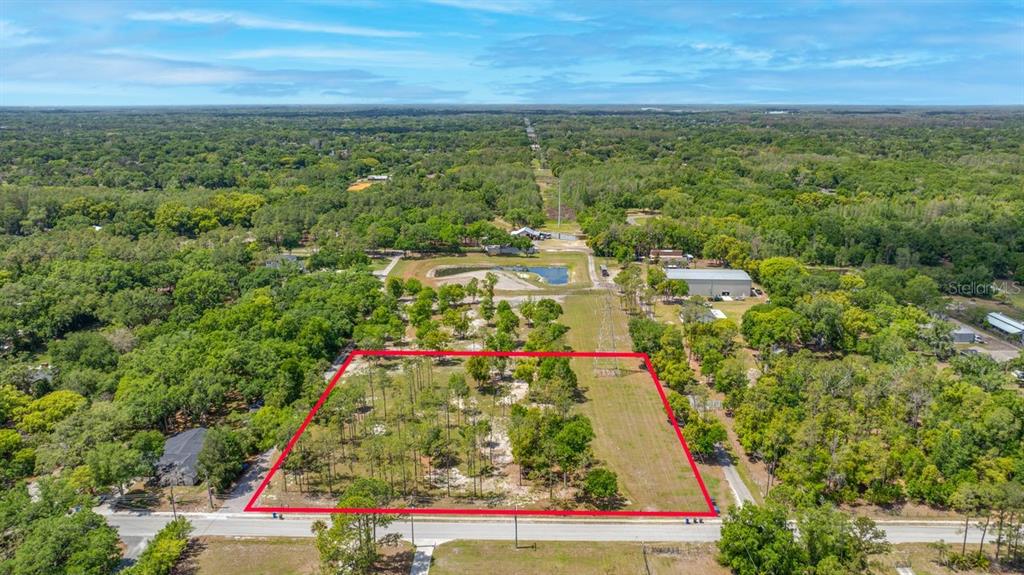 An aerial view shows a rectangular, partially wooded vacant lot outlined in red along a road — 0 HANNA ROAD, LUTZ, FL