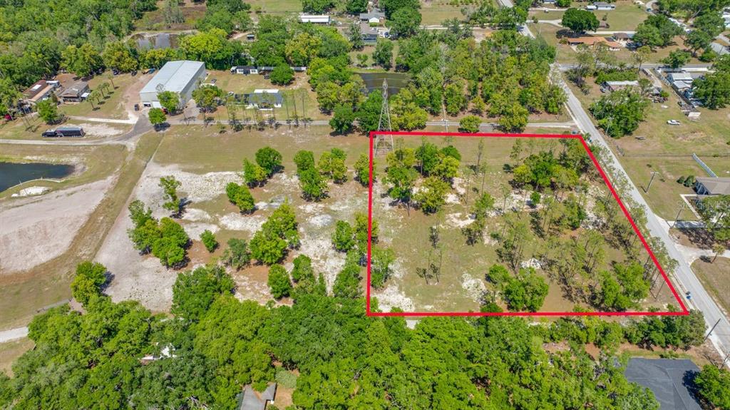 An aerial view shows a vacant, partially wooded lot outlined in red next to a road — 0 HANNA ROAD, LUTZ, FL