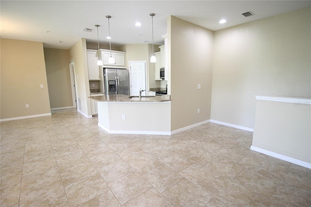 An open-concept kitchen features granite countertops, white cabinetry, stainless steel appliances, and tile flooring — 4248 EXPEDITION WAY, OSPREY, FL