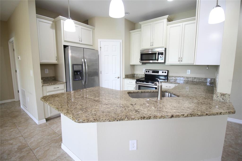 A kitchen features white cabinets, granite countertops, stainless steel appliances, and a peninsula sink — 4248 EXPEDITION WAY, OSPREY, FL