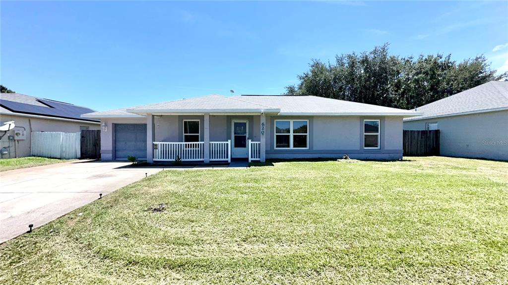 A single-story house with a white porch, gray siding, and a large front lawn — 620 BROCKTON DRIVE, KISSIMMEE, FL